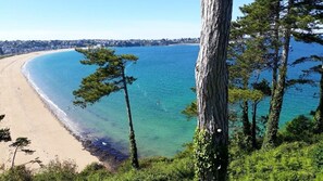 A coastal landscape with a sandy beach, clear blue water, and a line of trees. - Ti Kastrilhez - 1er - À 1 km de la plage (Saint-Cast-le-Guildo)