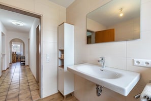 Un baño moderno con un lavamanos grande, espejo y estantes integrados.