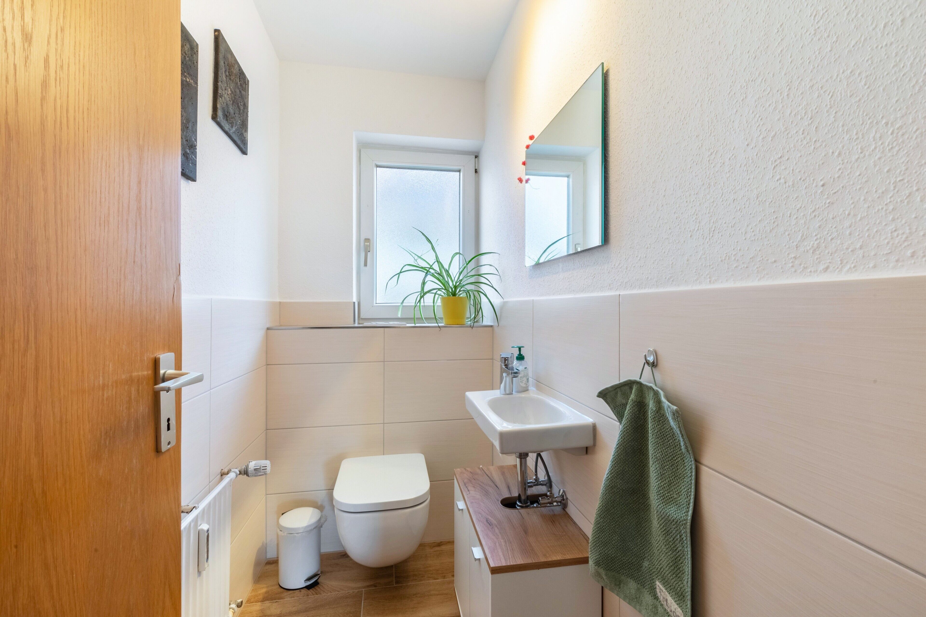 A compact bathroom with a toilet, sink, and a small window.