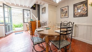 Een eetgedeelte met een ronde tafel, stoelen en een kroonluchter.