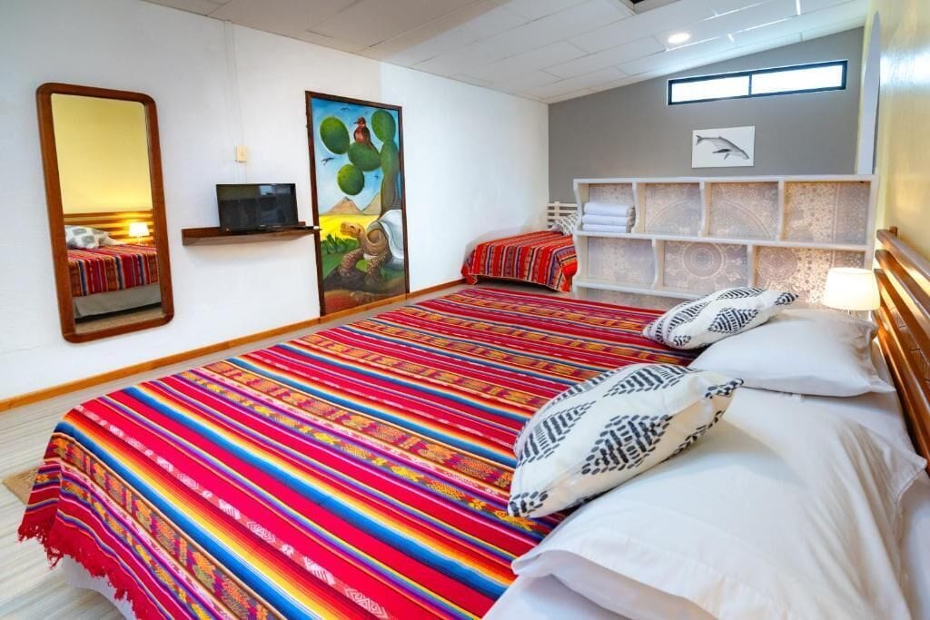 A hotel room with a large bed, a television, a painting, and a shelf with towels.