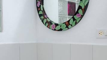 A bathroom with a white sink, a mirror with a floral frame, and a faucet.