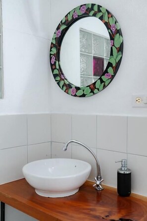Un baño con un lavabo blanco, un espejo con marco floral y un grifo.