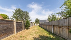 Ein Garten mit Holzzaun, einem kleinen Baum und einer Rasenfläche.