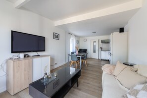 Ein modernes Wohnzimmer mit Flachbildfernseher, Holzschrank, Glastisch und einer Couch.