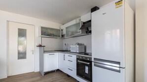 Eine kleine Küche mit weißen Schränken, einer Mikrowelle, einem Herd und einem Kühlschrank.