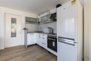 Eine kleine Küche mit weißen Schränken, einer Mikrowelle, einem Herd und einem Kühlschrank.