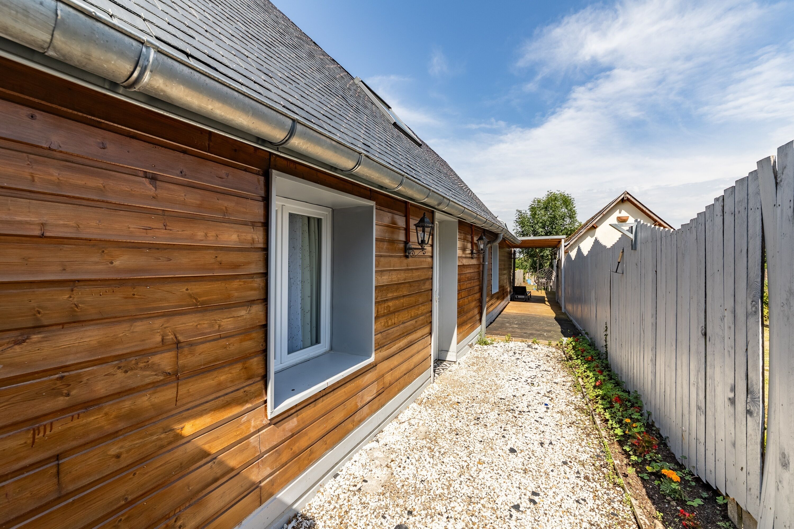 A wooden building with a gravel path and a wooden fence.
