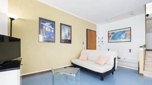 A living room with a sofa, a glass coffee table, a television, and wall art. - Charming 3-bedroom Apartment in Riccione With Free Parking (Riccione)