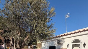 A building with a white exterior, a tiled roof, and a white fence. There is a satellite dish on the roof and a door with a window. - CASA al centro di Lacco Ameno: a piedi alle terme Negombo, mare e ristoranti (Lacco Ameno)