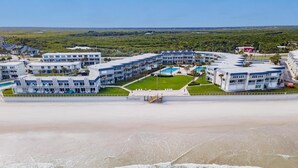 Un hôtel en bord de mer composé de plusieurs bâtiments, doté d’un espace piscine et donnant sur la plage.