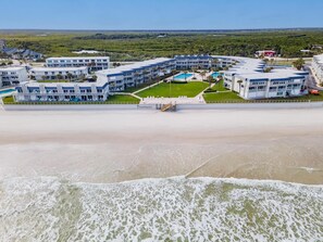 Ein Hotel direkt am Strand mit mehreren Gebäuden, einem Poolbereich und Strand im Vordergrund.