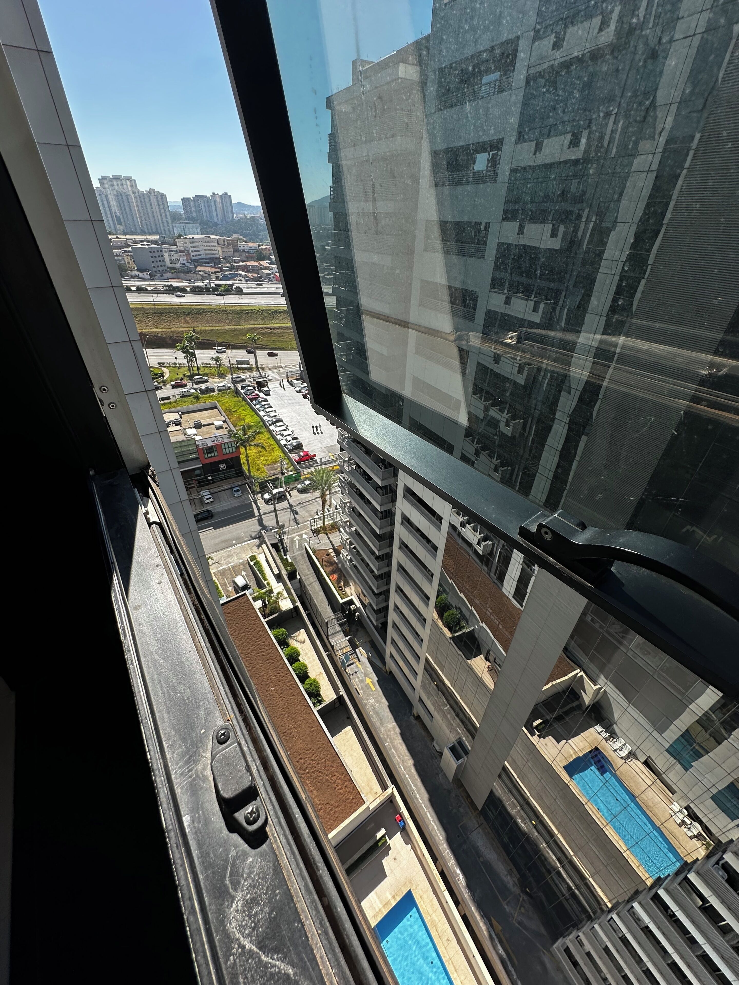 Un edificio alto con vista a un estacionamiento y una piscina.