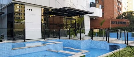 A modern building with a swimming pool, a covered seating area, and a visible address number 216.