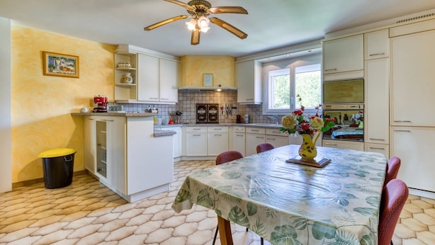 A kitchen with a dining area, a ceiling fan, and a window.