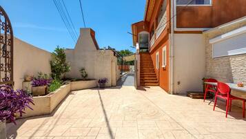 A courtyard with a tiled floor, a staircase, and a table with chairs.