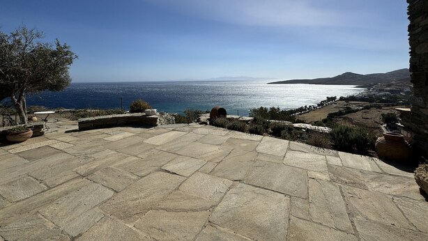 Une terrasse en pierre offrant une vue sur la mer et les collines lointaines.