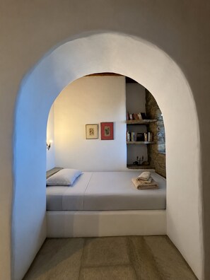 Ein gemütliches Zimmer mit einem eingebauten Bett, einer kleinen Ablage mit Büchern und einem gerahmten Bild an der Wand.