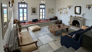Un salon spacieux doté d’une cheminée, d’un sol en pierre et d’une grande fenêtre.