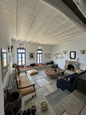 Ein geräumiges Wohnzimmer mit Kamin, Steinböden und einem großen Fenster.