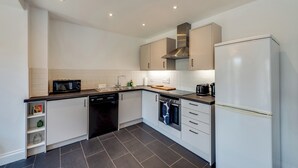 A modern kitchen with white cabinets, a dishwasher, a microwave, and a refrigerator. - Cosy 3BR House with free parking (Oxford)