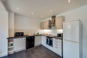 A modern kitchen with white cabinets, a dishwasher, a microwave, and a refrigerator. - Cosy 3BR House with free parking (Oxford)