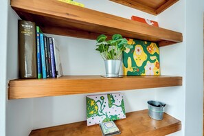 A shelf with books, a potted plant, a colorful card, and a metal container. - Cosy 3BR House with free parking (Oxford)