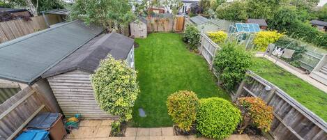 A residential backyard with a lawn, a wooden fence, and a shed.