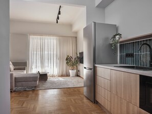 A modern kitchen with a built-in refrigerator, wooden cabinets, and a black faucet. - Xenios Athens Stay – 2 Bedroom Apartment (Athina)