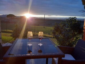 A table with two wine glasses and a view of the sunset over a vineyard. - Casale del Trebbio: Relax in the Umbrian Hills, Just 10 Minutes from Perugia (perugia)