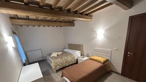 Ein Schlafzimmer mit zwei Betten, einem Schreibtisch und einer Holzbalkendecke.