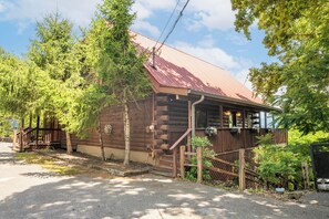A rustic log cabin with a metal roof, wooden porch, and a small staircase leading to the entrance. - 🏔️ Rendez-View | 4BR Mountain Escape | Theater, Game Room & Hot Tub | Sleeps 12 (Sevierville)