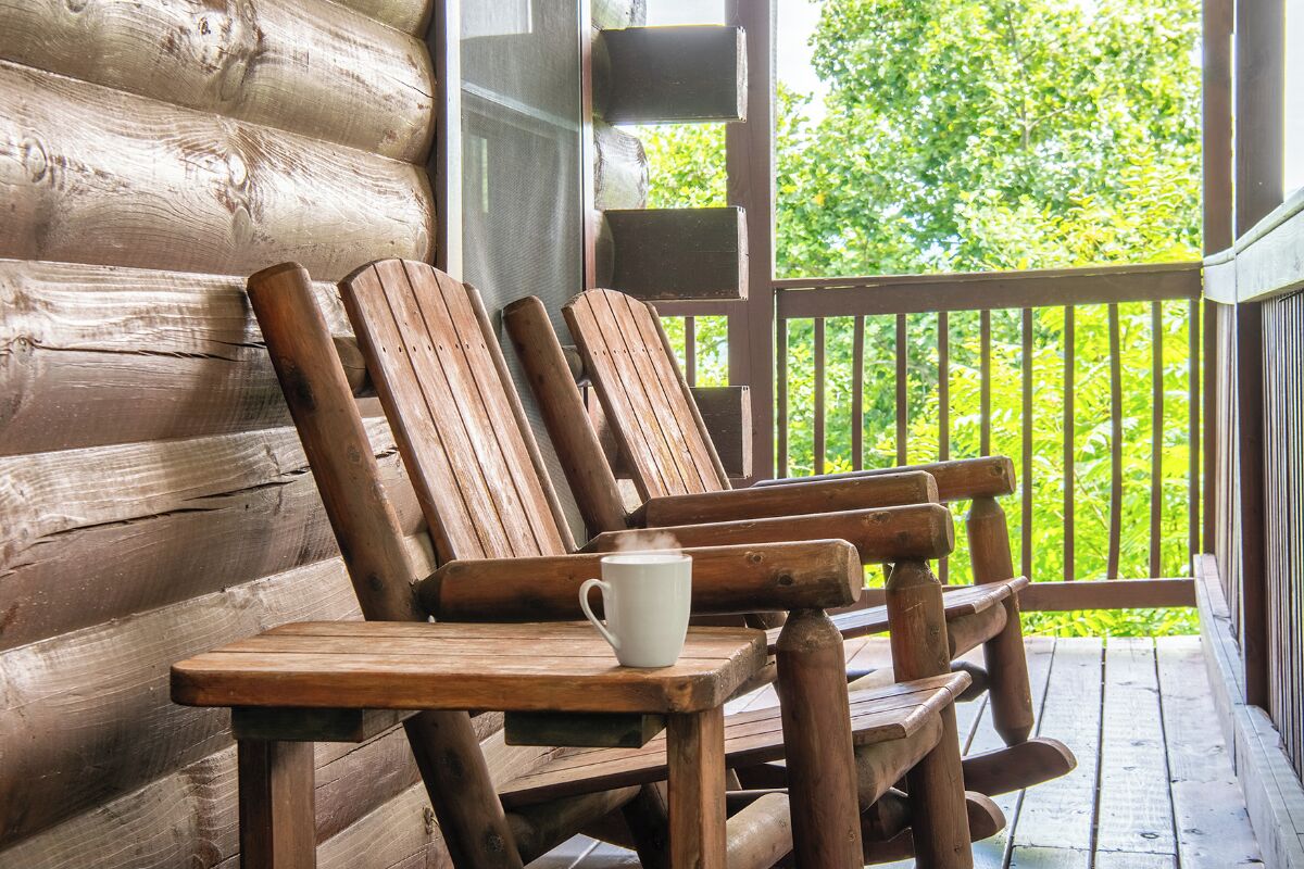 A wooden porch with a table and two wooden chairs.