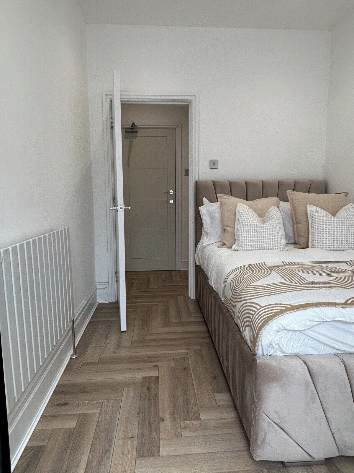 A bedroom with a bed, a door, and a radiator.