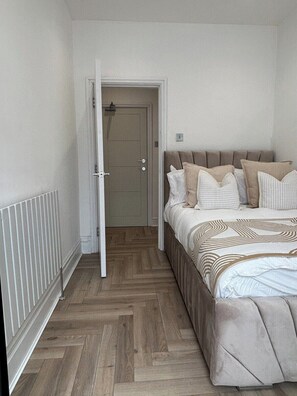 Um quarto com uma cama, uma porta e um radiador.
