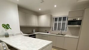 Een moderne keuken met een centraal eiland, witte kasten en een visgraat houten vloer.