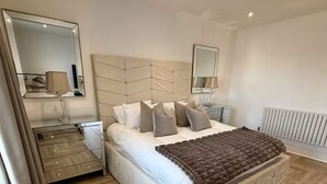 Een slaapkamer met een groot bed, houten vloeren en een radiator.