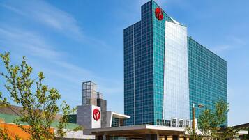 A modern hotel with a prominent glass facade, a central entrance, and a clear sky.