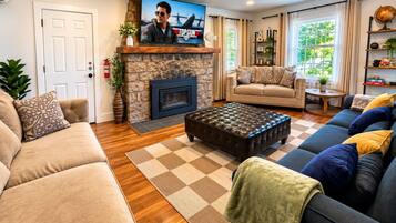 A living room with a fireplace, a television, a sofa, a coffee table, and a bookshelf.