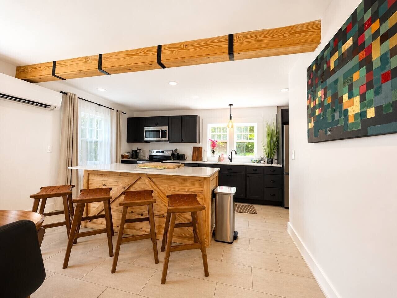 Una cocina moderna con una isla central, taburetes de bar y un comedor.