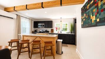 Una cocina moderna con una isla central, taburetes de bar y un comedor.