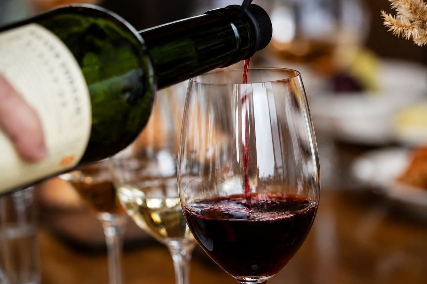 A wine bottle being poured into a wine glass.