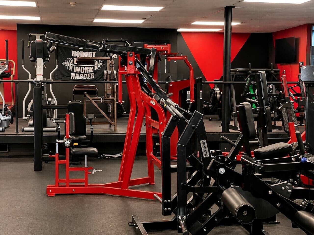 A gym with various exercise equipment, a motivational banner, and a mirror on the wall.