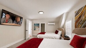 Quarto com duas camas, televisão e um quadro na parede.