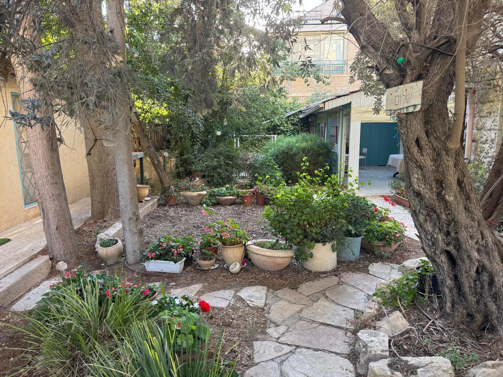 A courtyard with potted plants, a stone pathway, and a building with a balcony.