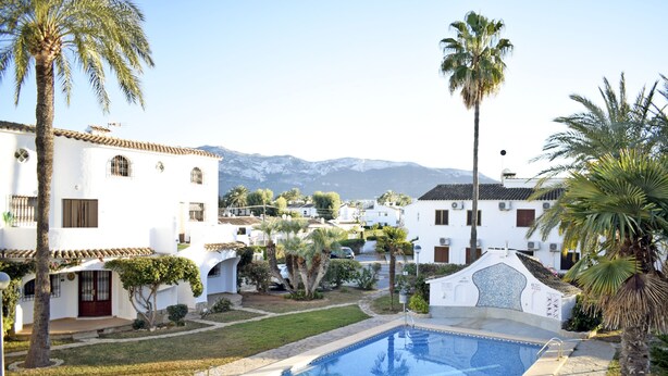 A pool area with a clear view of white buildings, palm trees, and a mountain in the background. - Ap1139 in Denia With 1 Bedrooms and 1 Bathrooms (Denia)