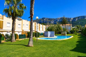 A resort with a swimming pool, palm trees, and mountain views. - Ad3202 in Denia With 3 Bedrooms and 2 Bathrooms (Denia)