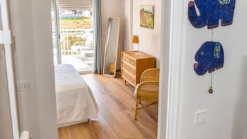 Une chambre à coucher avec un lit, une commode, un miroir et une vue sur l’extérieur.