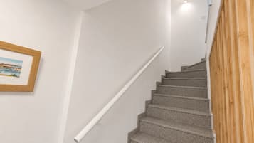 Un escalier muni d’une rampe, un tableau encadré au mur et un panneau en bois sur la droite.