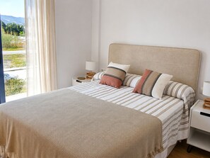 A bedroom with a bed, pillows, a bedside table, a lamp, and a view of the outdoors. - Ad1360 in Oliva With 3 Bedrooms and 1 Bathrooms (Oliva)